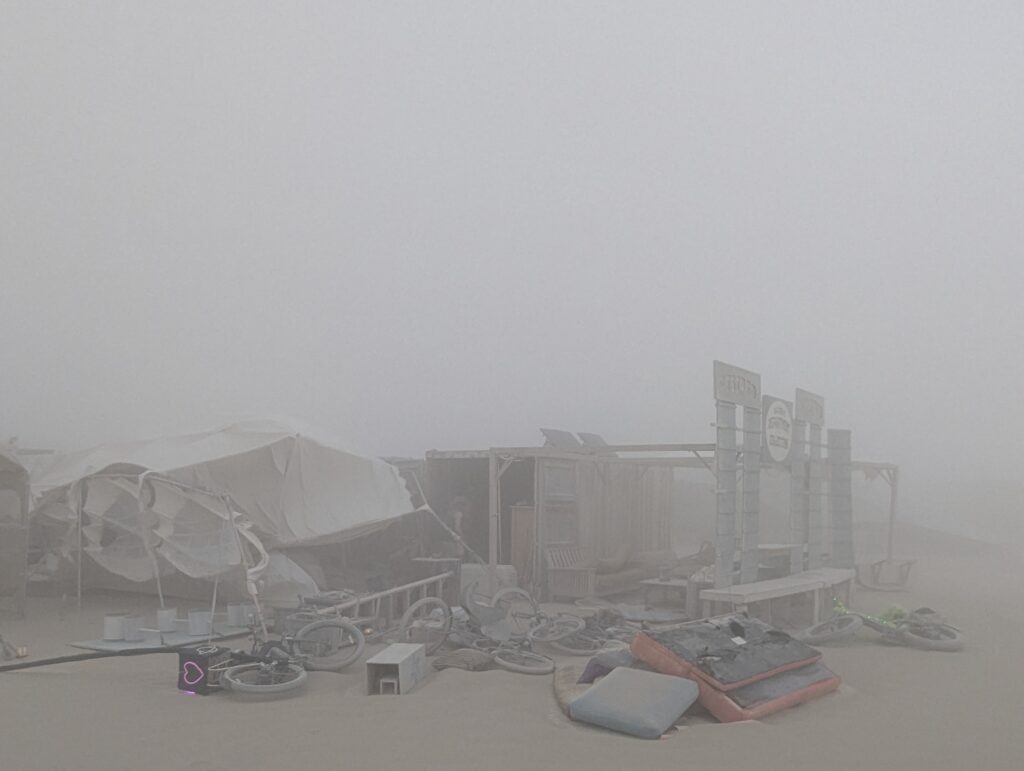 A photo of our camp frontage as the big dust storm subsided. A large event tent twisted and collapsed upon itself. Camp stuff strewn about.